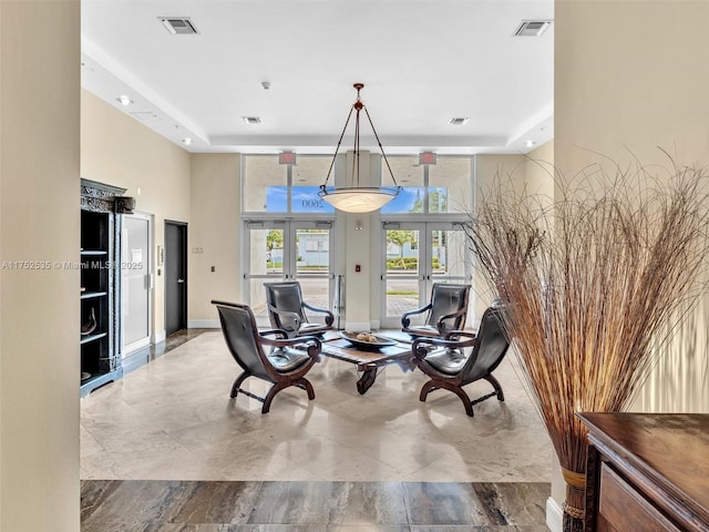 living area featuring visible vents, a raised ceiling, and french doors