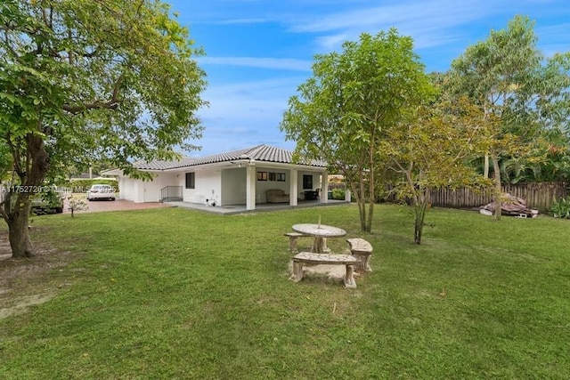 rear view of house with a yard, a patio area, fence, and a tiled roof