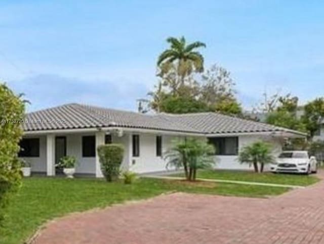 view of front of house featuring a tile roof, stucco siding, and a front lawn