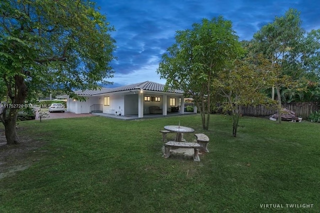 exterior space with a patio area, a tile roof, fence, and a lawn