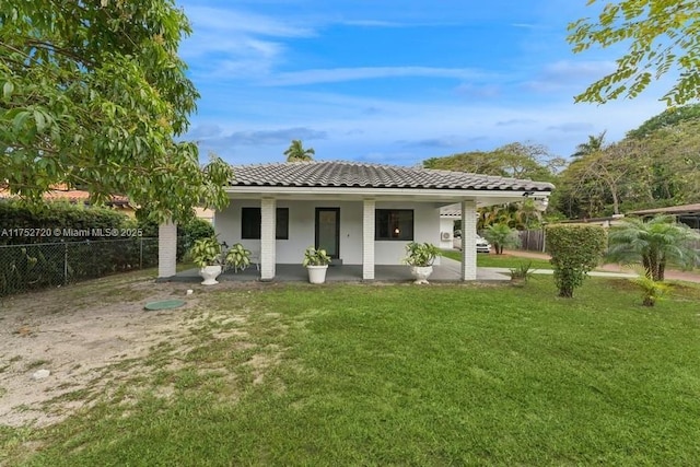 back of house with a tile roof, fence, and a yard
