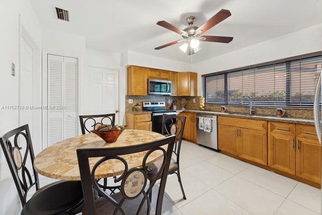 kitchen featuring visible vents, brown cabinetry, appliances with stainless steel finishes, a sink, and backsplash