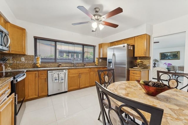 kitchen with a sink, a ceiling fan, brown cabinetry, stainless steel appliances, and decorative backsplash