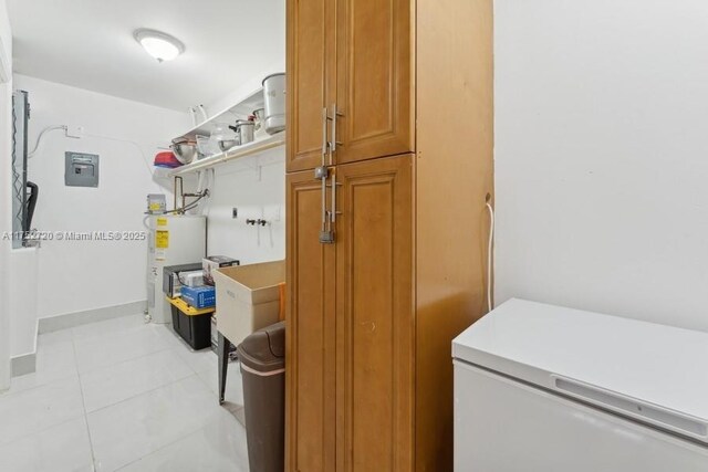 clothes washing area with water heater, light tile patterned floors, baseboards, laundry area, and electric panel
