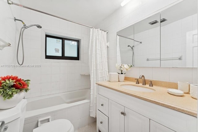 full bath with toilet, vanity, tiled shower / bath, and tile walls