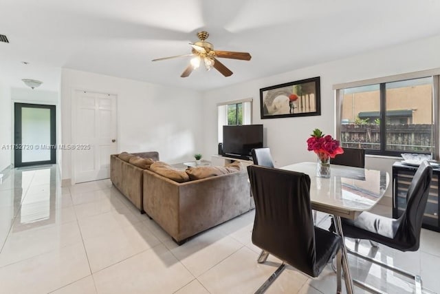 living room with light tile patterned flooring, visible vents, and a ceiling fan