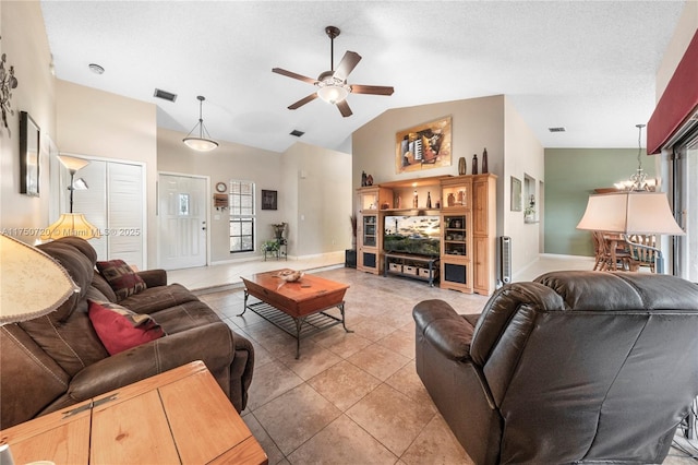 living area with light tile patterned floors, lofted ceiling, visible vents, a textured ceiling, and ceiling fan with notable chandelier