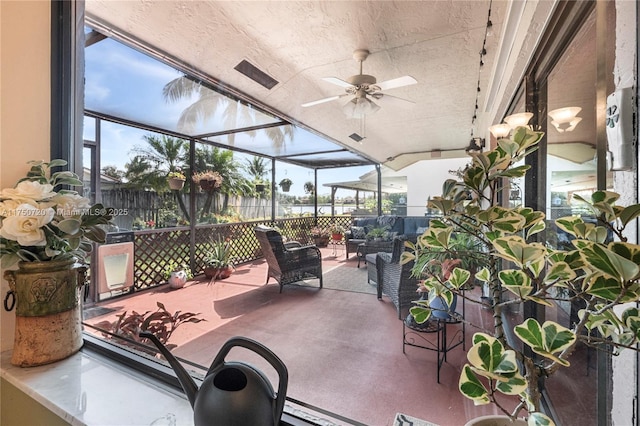 view of patio / terrace with glass enclosure, ceiling fan, fence, and an outdoor living space