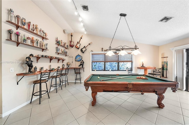 recreation room with lofted ceiling, visible vents, and a textured ceiling