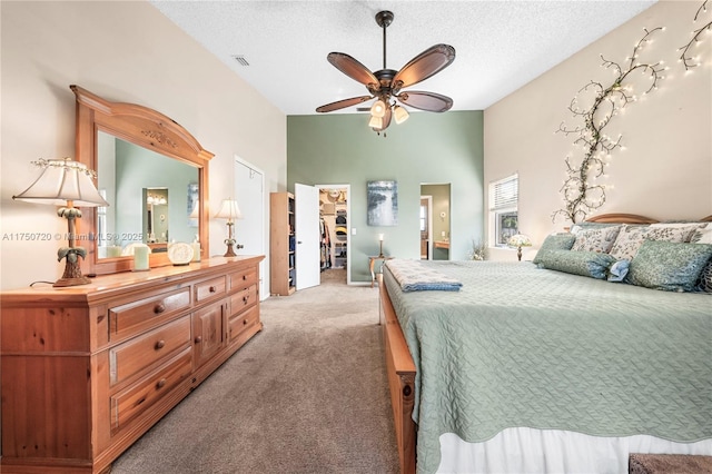 bedroom featuring light carpet, a spacious closet, a textured ceiling, and visible vents