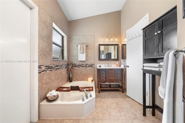 full bathroom featuring a garden tub, tile patterned flooring, vanity, and lofted ceiling