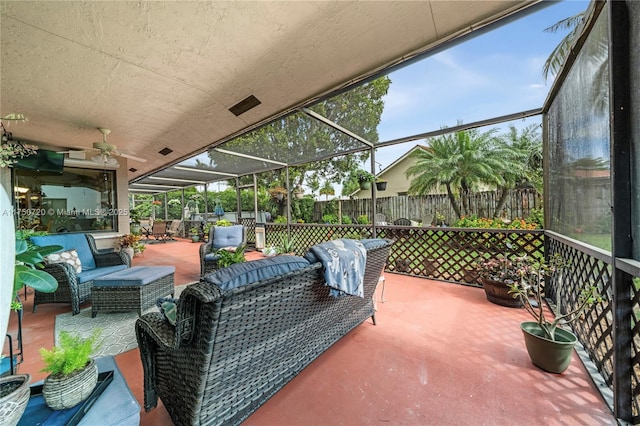 view of patio / terrace featuring a lanai, ceiling fan, fence, and an outdoor living space