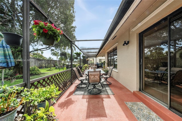 view of patio with outdoor dining area, fence, and a lanai