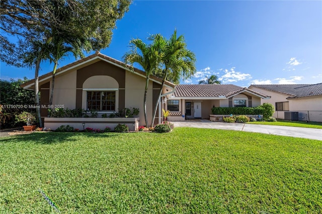 view of front facade with central AC, a tiled roof, a front lawn, and stucco siding