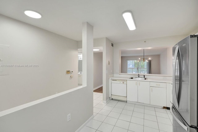 kitchen featuring white dishwasher, a sink, white cabinetry, light countertops, and freestanding refrigerator