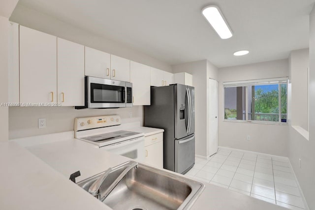 kitchen featuring light tile patterned floors, stainless steel appliances, a sink, white cabinets, and light countertops