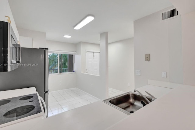 kitchen featuring visible vents, stainless steel microwave, electric range, a sink, and tile patterned flooring