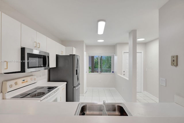 kitchen with light tile patterned floors, stainless steel appliances, light countertops, white cabinets, and a sink