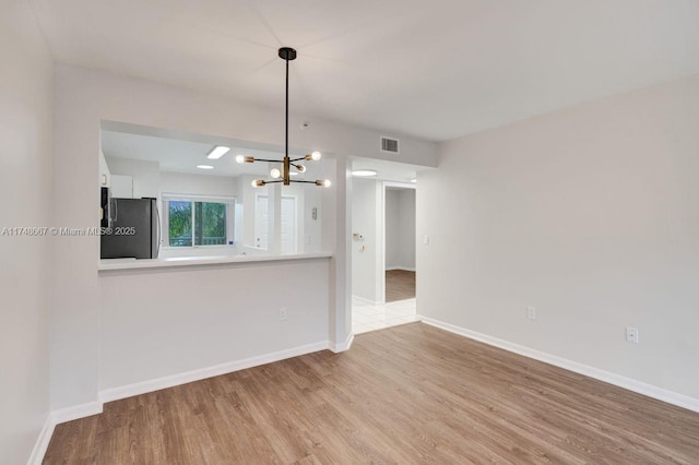 unfurnished living room featuring wood finished floors, visible vents, and baseboards