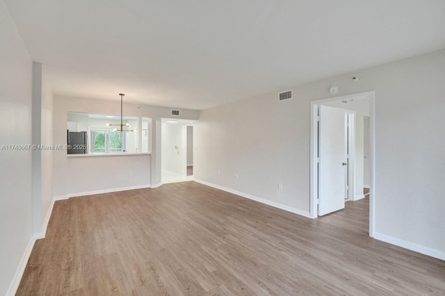 empty room featuring visible vents, baseboards, and wood finished floors