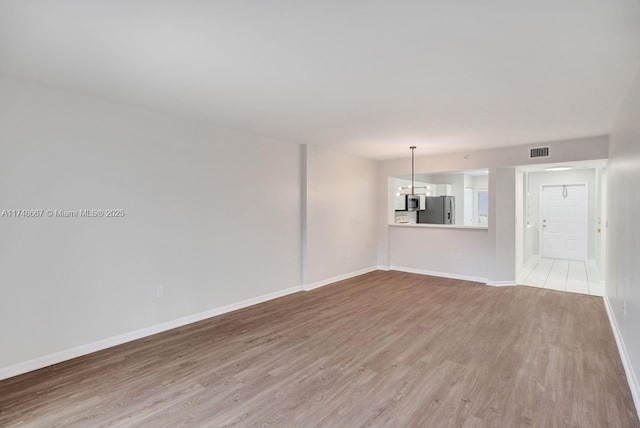 unfurnished living room featuring wood finished floors, visible vents, and baseboards