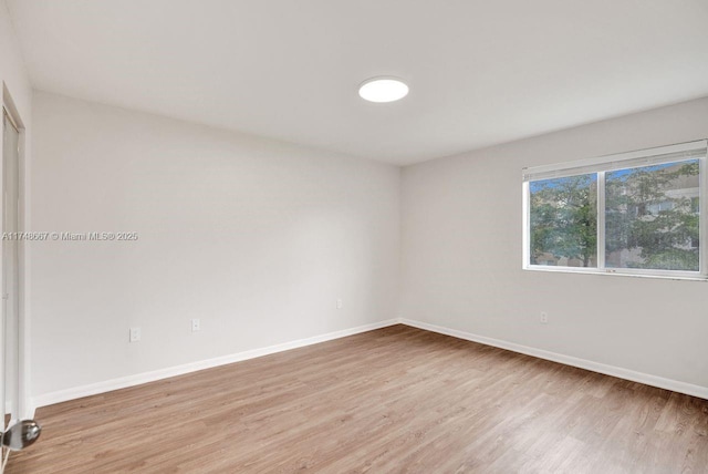 spare room featuring baseboards and light wood finished floors