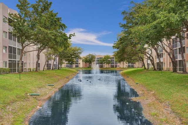 surrounding community with a water view and a lawn