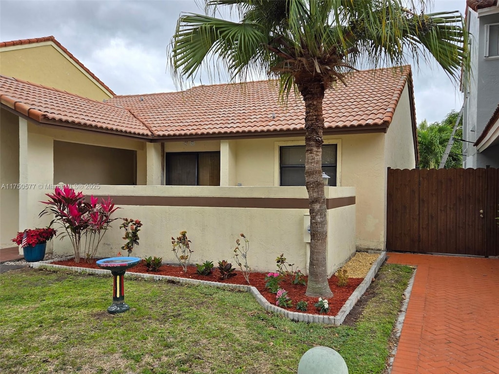 view of side of property with a tile roof, fence, a lawn, and stucco siding