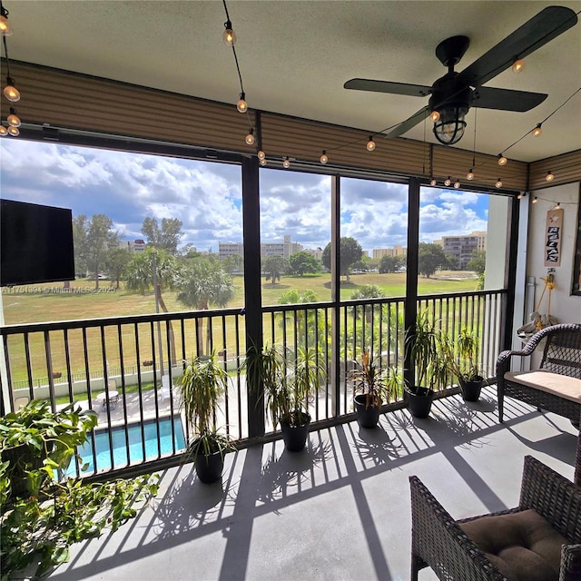 sunroom with golf course view and a ceiling fan