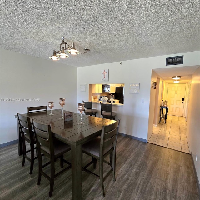 dining area featuring a textured ceiling, baseboards, dark wood-style floors, and visible vents