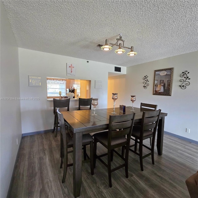 dining room featuring visible vents, baseboards, wood finished floors, and a textured ceiling