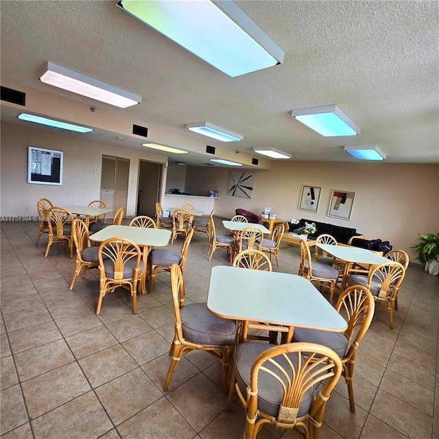dining room featuring light tile patterned floors, visible vents, and a textured ceiling