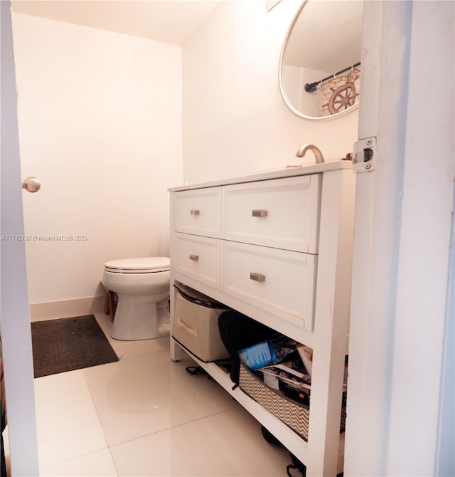 bathroom with toilet, baseboards, vanity, and tile patterned floors