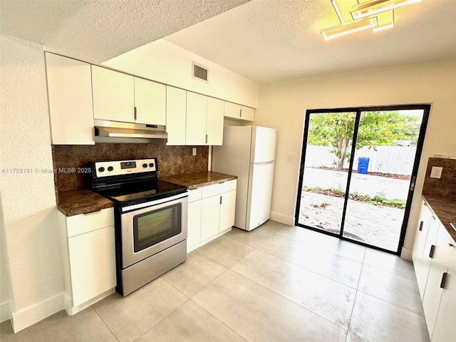 kitchen with dark countertops, tasteful backsplash, under cabinet range hood, stainless steel range with electric cooktop, and freestanding refrigerator