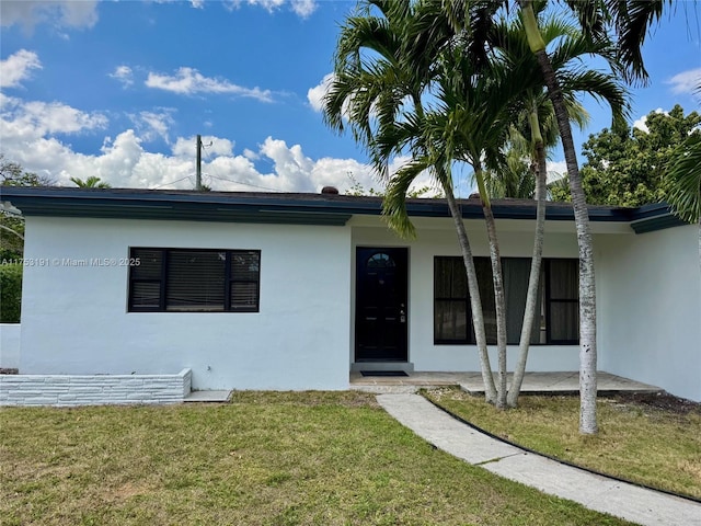 single story home with stucco siding and a front yard