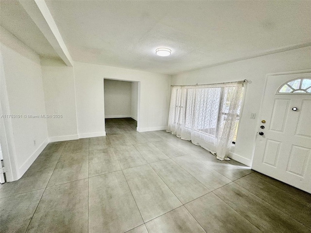 foyer entrance with tile patterned flooring, a textured ceiling, and baseboards