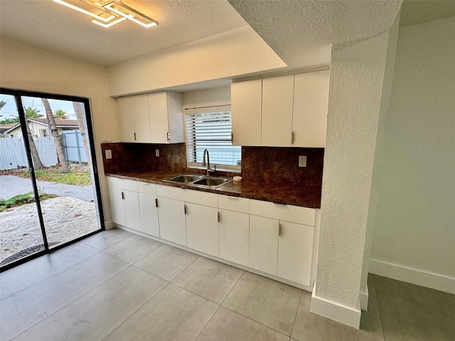 kitchen with a sink, backsplash, dark countertops, and a healthy amount of sunlight