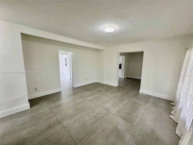 unfurnished room featuring a textured ceiling and baseboards