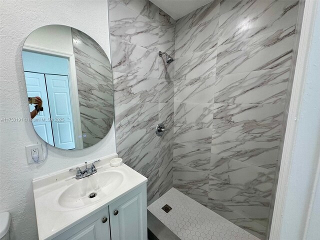 bathroom featuring vanity, toilet, and tiled shower