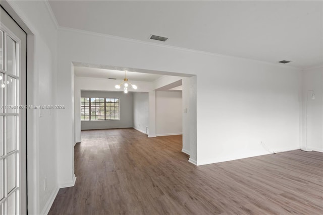 unfurnished room featuring ornamental molding, visible vents, baseboards, and wood finished floors