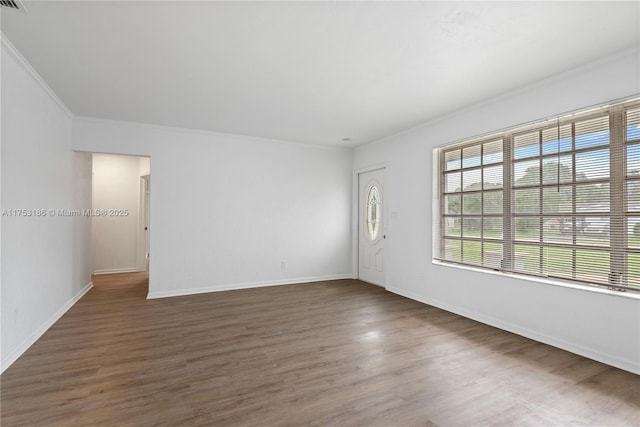 empty room featuring crown molding, baseboards, and wood finished floors