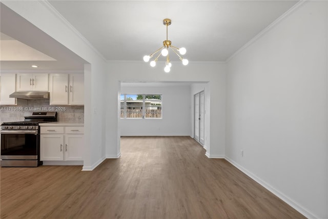 kitchen featuring stainless steel gas range oven, white cabinets, decorative backsplash, ornamental molding, and under cabinet range hood