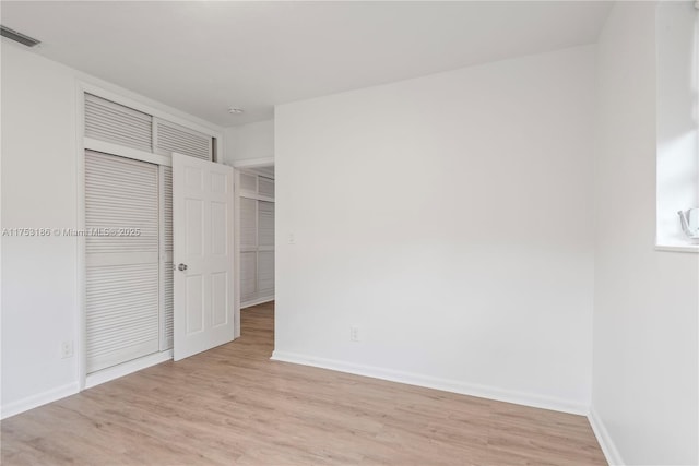 unfurnished bedroom with light wood-type flooring, a closet, visible vents, and baseboards