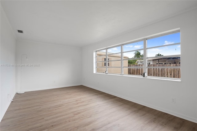 unfurnished room with visible vents, baseboards, and wood finished floors