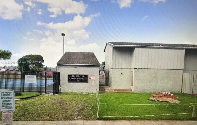 exterior space featuring a gate, fence, and a lawn