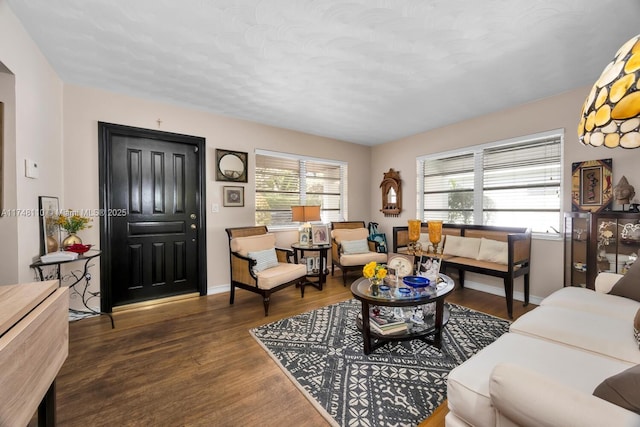 living area featuring a healthy amount of sunlight, baseboards, and dark wood-style flooring