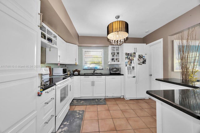 kitchen featuring dark countertops, white appliances, white cabinets, and a sink