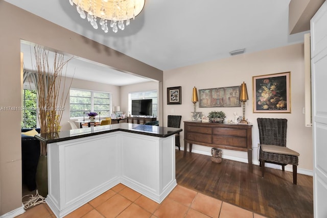 kitchen featuring dark countertops, open floor plan, white cabinets, and a notable chandelier