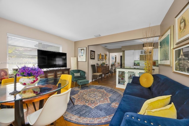 living area featuring visible vents, a chandelier, and wood finished floors