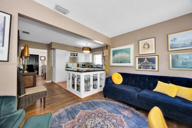 living room featuring a chandelier, visible vents, and wood finished floors